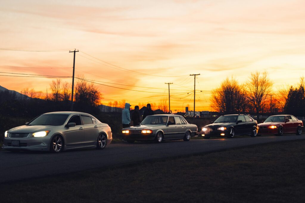 Modified cars parked at sunset, showcasing automobile culture and enthusiasts.